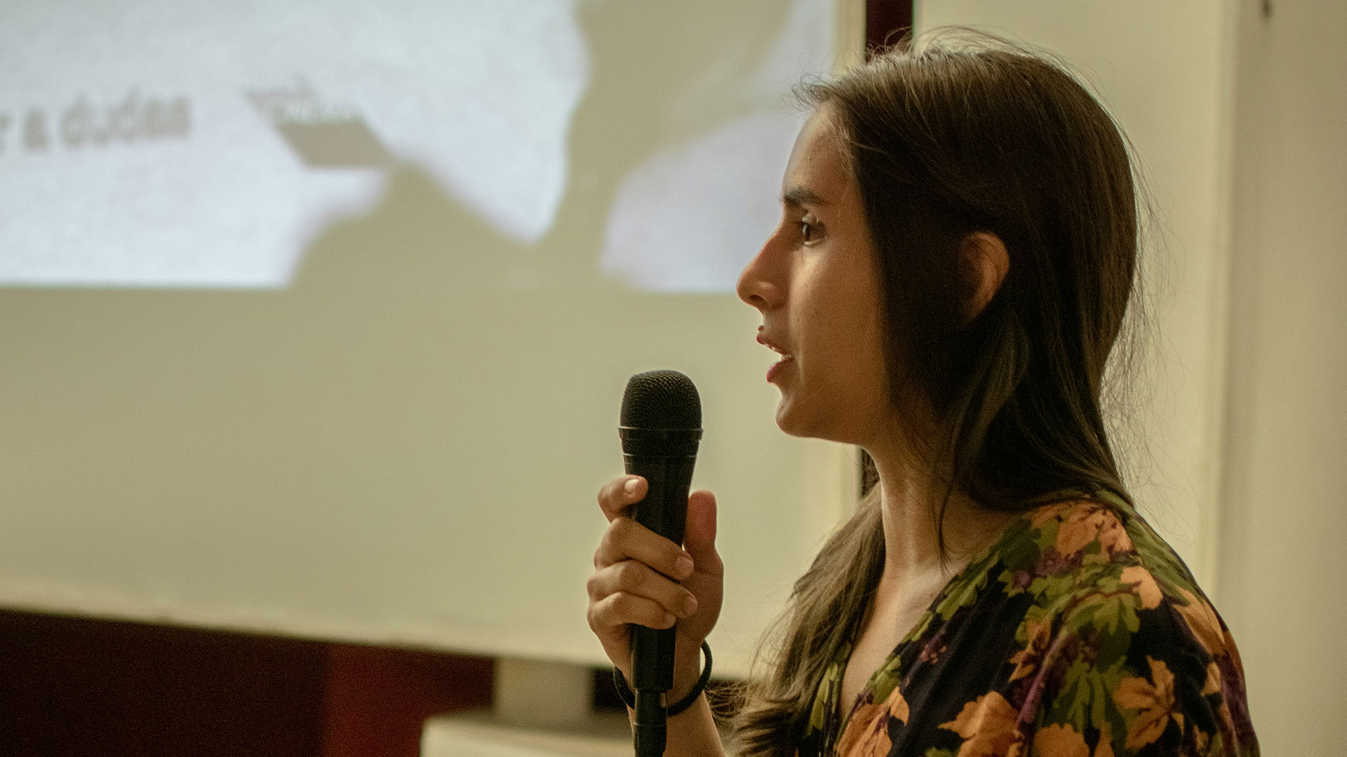 Fotografía a color de una mujer sosteniendo un microfono